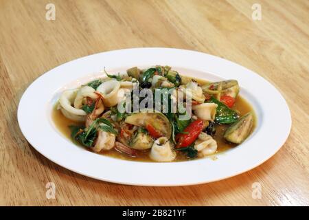 Frittura di pesce piccante su un piatto bianco - piatto al tavolo di legno, frutti di mare piccanti, cibi piccanti, Pad-cha Talay (parola tailandese) Foto Stock