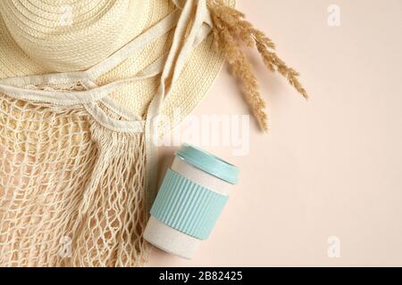 Accessori femmina a posa piatta zero scarti. Borsa da shopping riutilizzabile con vista dall'alto, tazza da caffè eco-compatibile con fibra di bambù, cappello da spiaggia in paglia e fiori secchi. Foto Stock