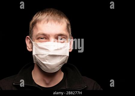 un uomo in una maschera medica protettiva dalle infezioni, qualcosa è felice e ridente, in un momento in cui il mondo sta infuriando epidemie e un coronavirus pa Foto Stock