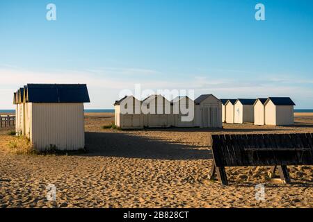 Riva Bella spiaggia cabine in legno al tramonto in una giornata di sole, Ouistreham, costa della Normandia, Francia. Foto Stock