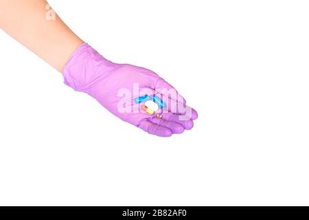 Vista superiore a portata di mano in lattice viola guanto medico che tiene un sacco di pillole isolato su bianco. Primo piano. Medicina o concetto di trattamento di salute. Foto Stock