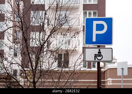 Parcheggio con segnaletica stradale per persone su sedia a rotelle e conducenti disabili nell'area riservata alle persone disabili. Foto Stock