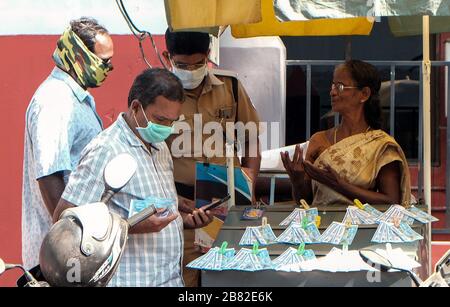 Kochi, India. 19 Mar 2020. I clienti che indossano la maschera e acquistano i biglietti della lotteria da un venditore a Kochi, Kerala, India, 19 marzo 2020. Credit: Str/Xinhua/Alamy Live News Foto Stock