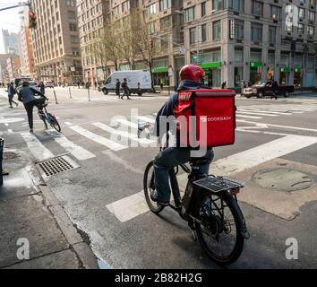 Un addetto alla consegna con una borsa tote con marchio DoorDash sulla sua bicicletta nel quartiere Chelsea di New York, venerdì 13 marzo 2020. (© Richard B. Levine) Foto Stock