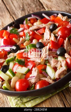 Insalata di tonno mediterranea con verdure fresche e fagioli primo piano in un piatto sulla tavola. Verticale Foto Stock