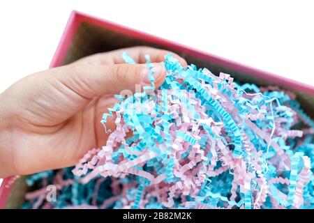 La mano tocca i trucioli di carta in una scatola. Carta da imballaggio sottile. Foto Stock