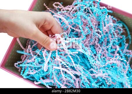 Trucioli di carta in una scatola. Carta sottile per un regalo. Le mani tocca ed esamina. Foto Stock