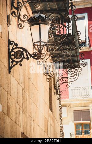 Spagna Turismo: Street view e Hanging Street Lamp su Brick Walls in Alilcante, Spagna Foto Stock