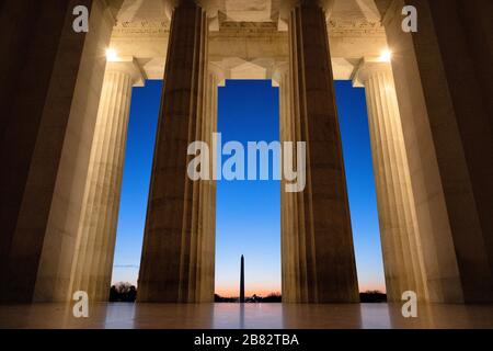 Lincoln Memorial View of Washington Monument Washington DC // WASHINGTON DC - Una vista dall'interno della camera principale del Lincoln Memorial, guardando attraverso le enormi colonne verso il Washington Monument poco prima dell'alba. Foto Stock