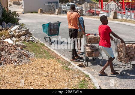 Zwelihle, Hermanus, Capo Occidentale, Sudafrica. Dic 2019. I giovani raccolgono vecchi mattoni nei carrelli per lo shopping sulla strada della cittadina di Zwelihle a Herma Foto Stock