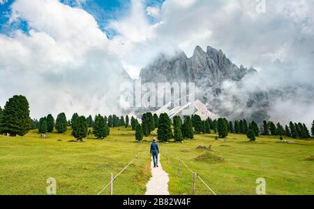 Escursionista su un sentiero escursionistico al Gschnagenhardt Alm, nuvoloso Geisler cime, Geisler gruppo con Sass Rigais, Val Villnoess, Dolomiti, Alto Adige Foto Stock