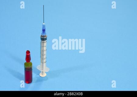 Fiala con vaccino e siringa su sfondo blu, concetto di medicina e panacea per tutti i virus, spazio di copia Foto Stock