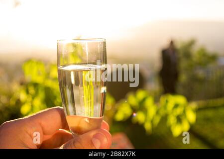 Bere un bicchiere di champagne di fronte a un meraviglioso paesaggio al tramonto, celebrando con felicità Foto Stock