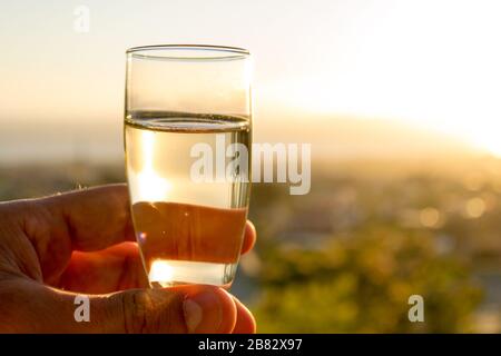 Bere un bicchiere di champagne di fronte a un meraviglioso paesaggio al tramonto, celebrando con felicità Foto Stock