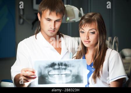 Giovane coppia uomo e donna in clinica dentale, guardando il quadro dentale. Concetto di salute dentale e di assistenza medica Foto Stock