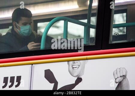Stratford, Londra, Regno Unito. 19 marzo 2020. Un uomo che indossa una maschera chirurgica siede sull'autobus nella stazione degli autobus di Stratford. La gente in fretta di comprare gli articoli restanti intorno al centro commerciale di Stratford dovuto il coronavirus si è sparso a Londra. Credit: Marcin Nowak/Alamy Live News Foto Stock