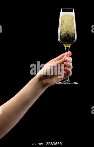 Donna mano che tiene un bicchiere di champagne frizzante isolato su nero. Foto Stock