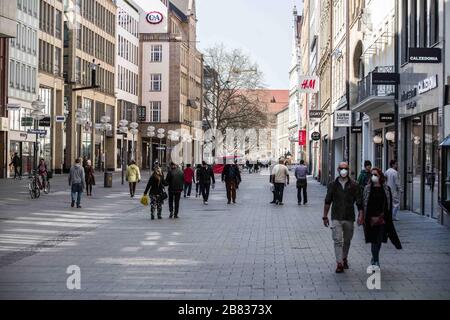 Monaco, Baviera, Germania. 19 Mar 2020. Due turisti indossano maschere facciali nelle strade relativamente vuote del centro di Monaco, in Germania. Normalmente, queste strade sono piene di decine di migliaia provenienti da tutto il mondo. In risposta al sempre più drammaticante Coronavirus (Sars cov 2, Covid 19), lo Stato della Baviera ha istituito misure che limitano le attività di vari tipi di imprese che hanno portato al centro della città, un tempo pieno di decine di migliaia di turisti e residenti, diventare una città fantasma virtuale, con un numero limitato di persone in vista. (Credit Image: © Sachelle Foto Stock