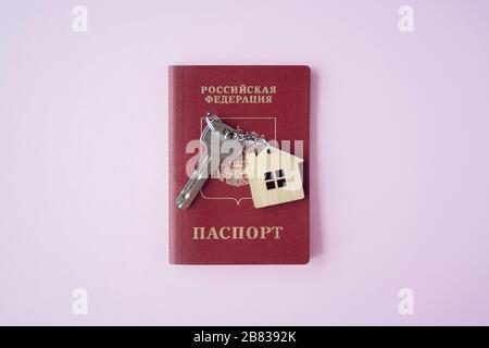 Russian International Passport e chiave con trinket casa su di esso su sfondo rosa primo piano su copia spazio. Immigrazione, emigrazione, cittadinanza Foto Stock