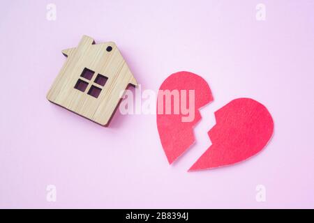 Divorzio, divisione della proprietà, povertà e nessun concetto di denaro. Casa di legno con cuore rotto su sfondo rosa brillante. Ipoteca, affitto, realtor Foto Stock