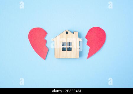 Divorzio, divisione della proprietà, povertà e nessun concetto di denaro. Casa di legno con cuore rotto su sfondo blu brillante. Ipoteca, affitto, realtor Foto Stock