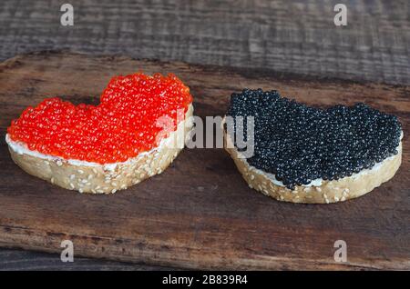 Panini con caviale a forma di cuore su un tagliere Foto Stock