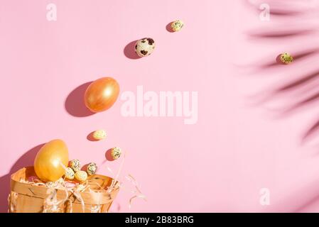 Carta per le vacanze di Pasqua con ombre da foglie di palme tropicali, pollo dipinto d'oro e uova di quaglia su uno sfondo rosa pastello. Foto Stock