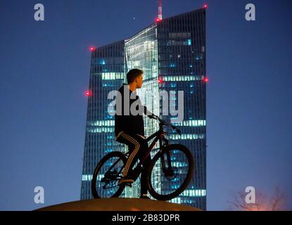 19 marzo 2020, Hessen, Francoforte sul meno: Un giovane è in piedi con la sua moto di fronte alla Torre ECB. Nonostante la pandemia della corona, la gente sta passeggiando lungo le rive del Main e nel parco portuale parzialmente chiuso. Foto: Andreas Arnold/dpa Foto Stock