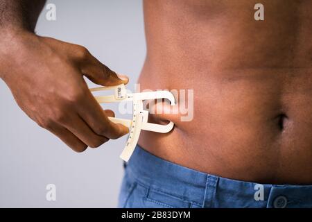 Close-up di uomo misura grasso dello stomaco con pinza Foto Stock