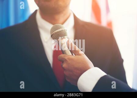 Immagine di un microfono che intervista un dirigente che indossa una tuta Foto Stock