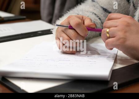 Primo piano sulle mani di una donna tenendo una penna sopra una nota. Foto scattata a Beirut, Libano Block su un tavolo da riunione in una sala conferenze Foto Stock