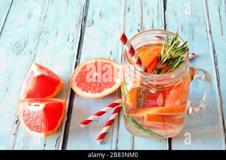 Pompelmo, rosmarino detox acqua in un vaso di muratura vetro vista verso il basso su uno sfondo rustico legno blu Foto Stock