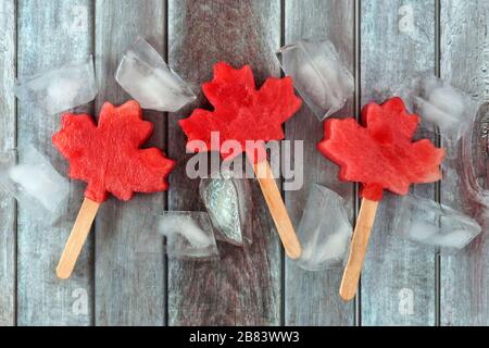 L'anguria canadese in foglia di acero si popola con cubetti di ghiaccio su uno sfondo rustico di legno invecchiato Foto Stock