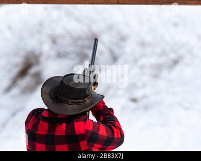 uomo con cappello cowboy che spara con un fucile Foto Stock