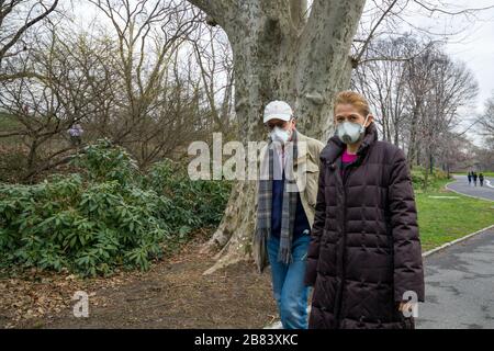 New York, USA, 19 Mar 2020. Una coppia indossa maschere facciali mentre passeggi a Central Park. La gente a New York sta usando le maschere e osservando la distanc sociale Foto Stock