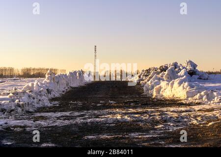 liberato di neve il percorso verso la torre cellulare, una striscia di terra libera in un campo o prato su cui l'anno scorso è visibile l'erba appassita Foto Stock