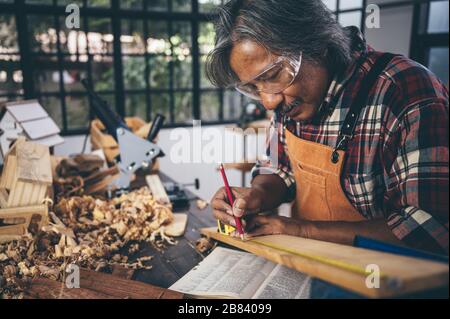 Immagine di sfondo di officina per la lavorazione del legno: carpentieri al tavolo di lavoro con diversi strumenti e taglio di legno stand, vintage immagine del filtro Foto Stock