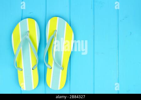 Un paio di infradito estivo su sfondo di legno blu Foto Stock