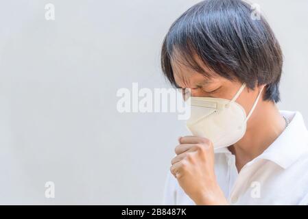 Un uomo asiatico indossa maschera N95 e tosse azione Foto Stock