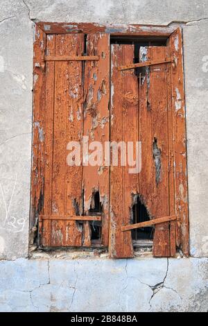 La finestra con l'otturatore in legno intemperato marrone con i fori in un vecchio edificio del villaggio Pano Lefkara. Cipro Foto Stock