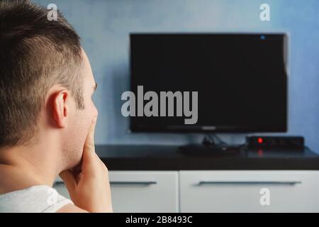tempo libero, tecnologia, mass media e concetto di gente - uomo che guarda la tv a casa da dietro. Il televisore non funziona Foto Stock