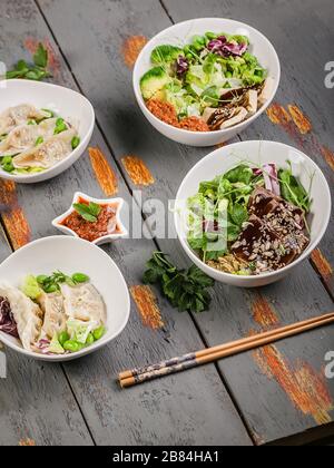 Gnocchi di gyozu tradizionali a colpo verticale, verdure bollite con riso, maiale e salsa piccante. Cucina orientale Foto Stock