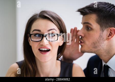 Primo Piano Di Uomo D'Affari Whispering In Female Partner'S Ear Foto Stock