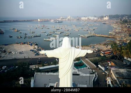 Statua di Gesù Cristo incontra barche da pesca alla spiaggia di Kovalam in Kerala, India Foto Stock