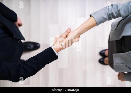 Direttamente Sopra Shot Di Uomini D'Affari Che Scuotono Le Mani Mentre Si Sta In Piedi Su Pavimento Piastrellato In Ufficio Foto Stock