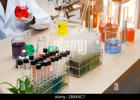 Campioni per test di laboratorio o laboratorio di ricerca medica o una soluzione con pipetta e vassoio per cellule a novantasei pozzetti con microscopi in background. Foto Stock