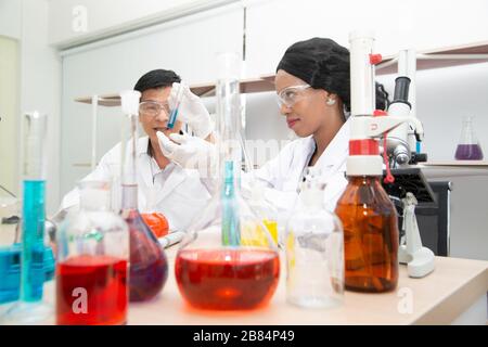 Due scienziati lavorano in laboratorio. Giovane ricercatore femminile e il suo superiore supervisore stanno facendo indagini sulle apparecchiature di laboratorio. Foto Stock