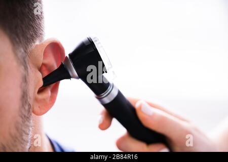 Close-up di un medico donna esaminando orecchio del paziente con otoscopio Foto Stock