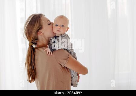 Madre baciando e abbracciando baby Foto Stock