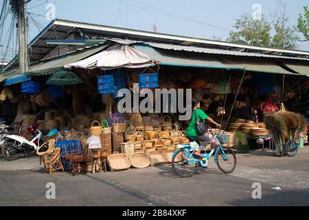 I clienti fanno un giro in bicicletta attraverso la parte anteriore del negozio che vende macchine tessili. Realizzato in bambù e rattan al mercato di Rong Kluea, provincia di SA Kaeo. Foto Stock